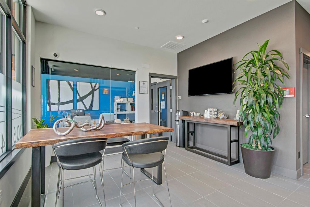A living room with a table , chairs , a plant and a flat screen tv.