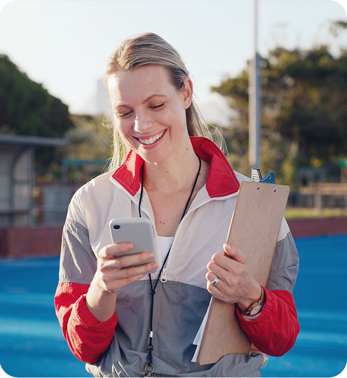 A woman is holding a clipboard and looking at her phone.