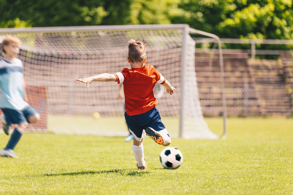 A young boy is kicking a soccer ball on a field.