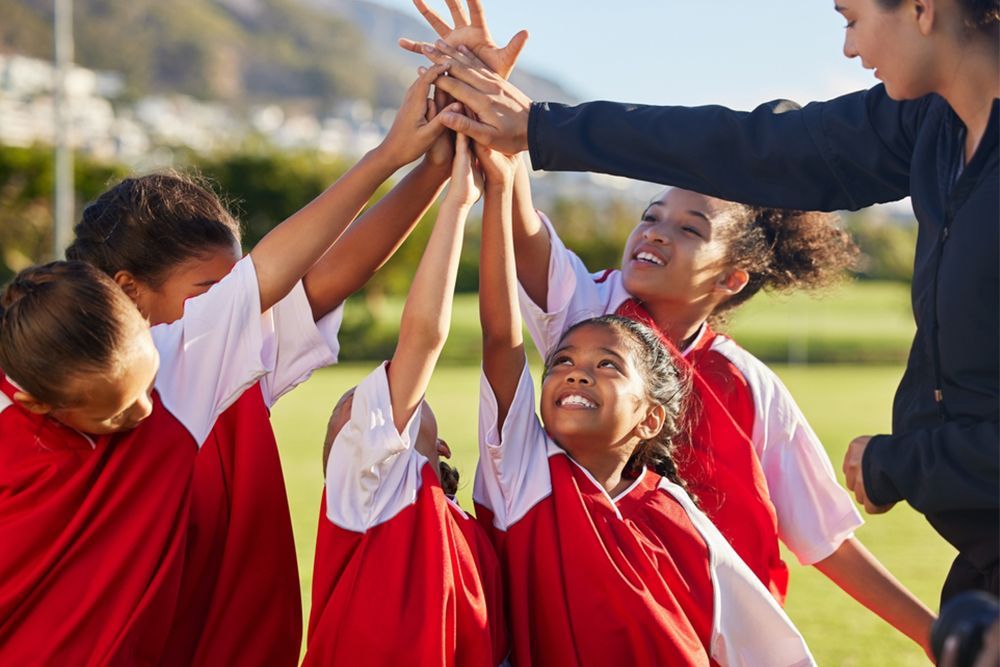 A group of young girls are giving each other a high five.