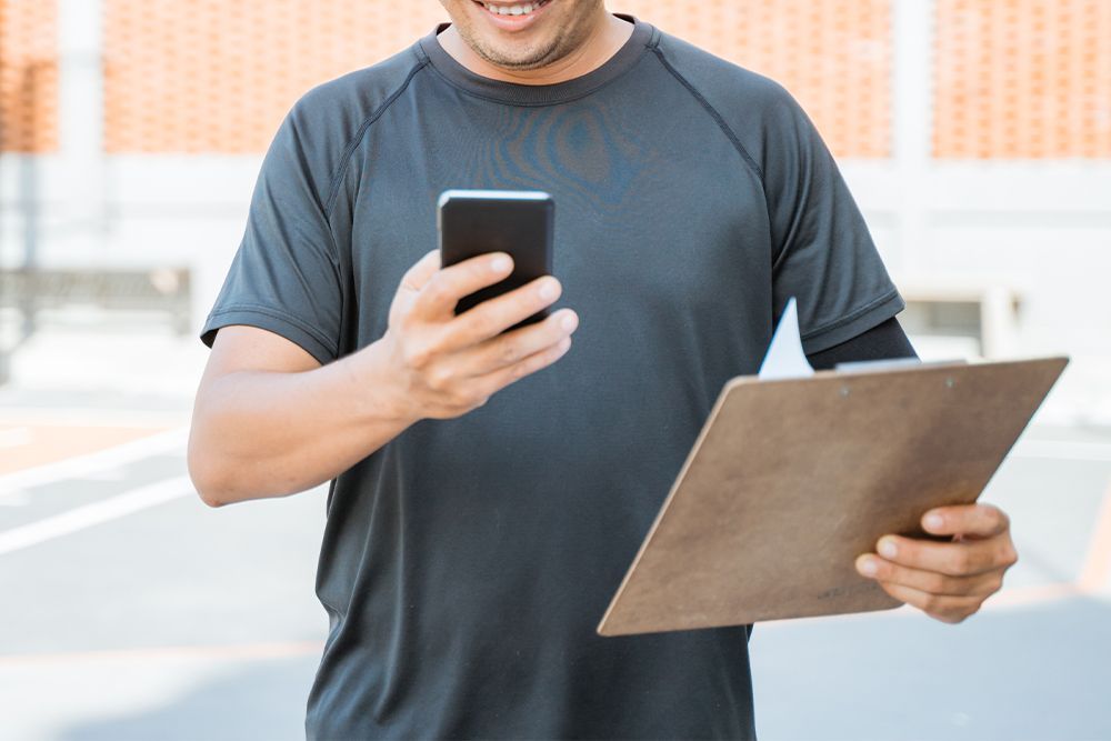 A man is holding a clipboard and a cell phone.