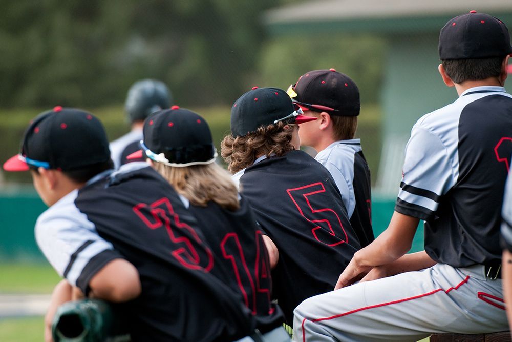 A group of young baseball players are sitting on a bench.