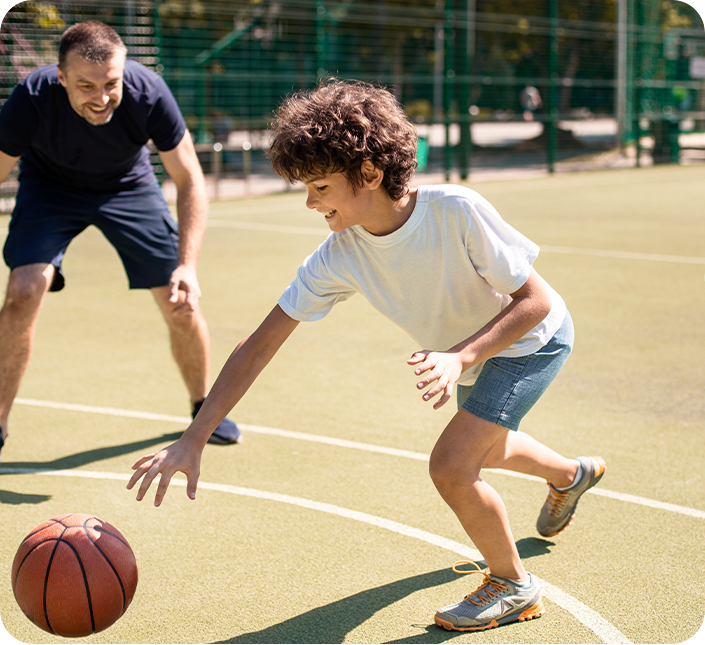 A man and a boy are playing basketball on a court.
