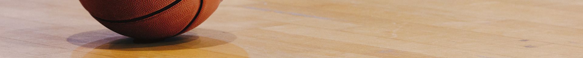 A basketball is spinning on a wooden floor.