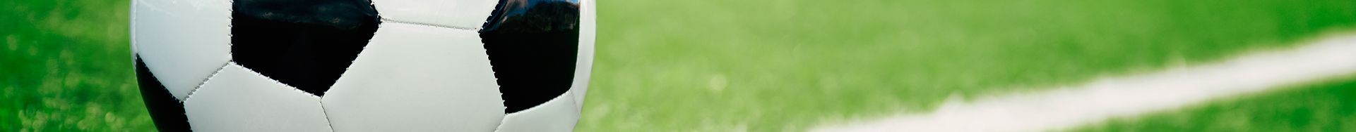 A black and white soccer ball is sitting on top of a green field.