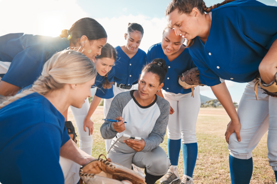 A group of female baseball players are huddled together on a field.