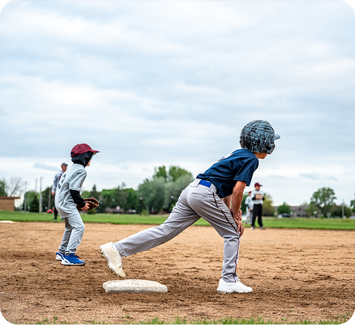 Two young boys are playing baseball on a dirt field.