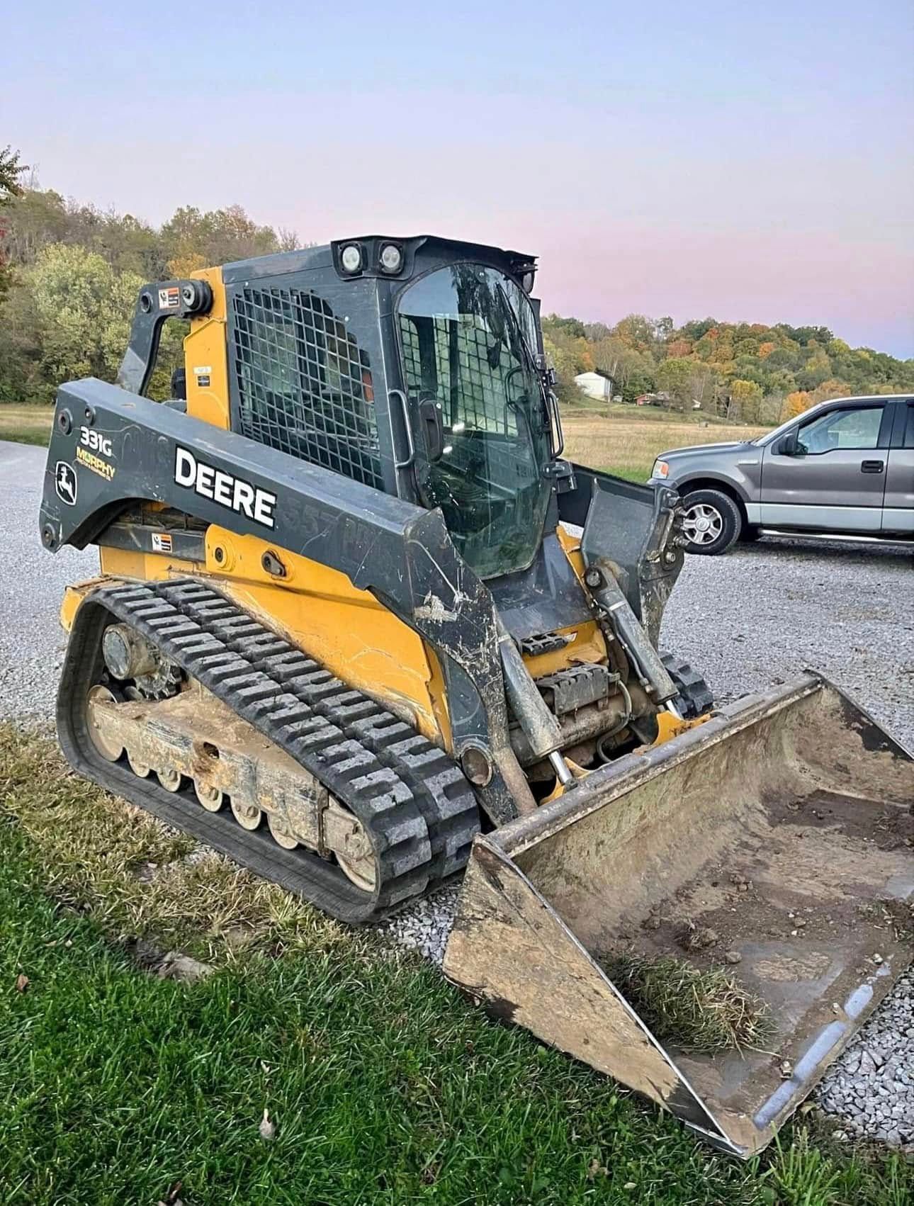Yellow and black John Deere skid steer loader parked outdoors.