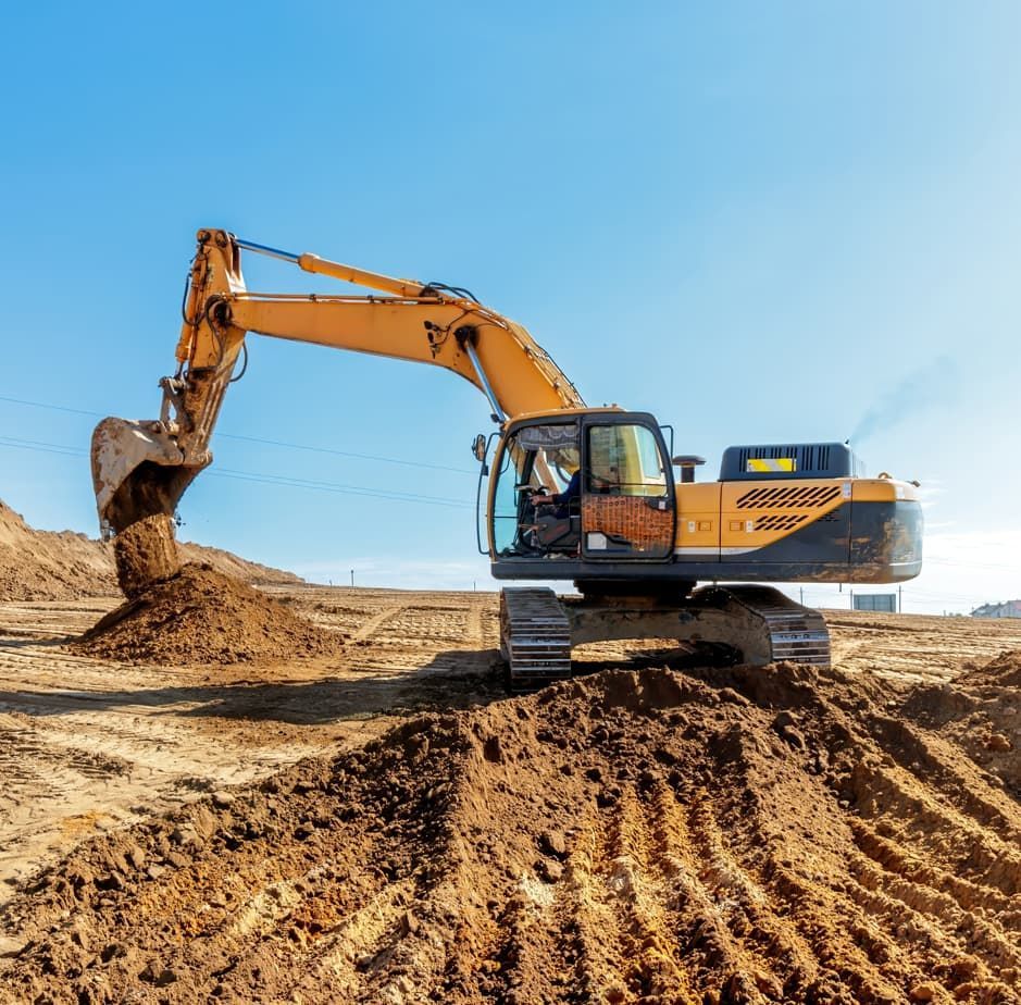 Yellow excavator digging dirt on a construction site under a clear blue sky.