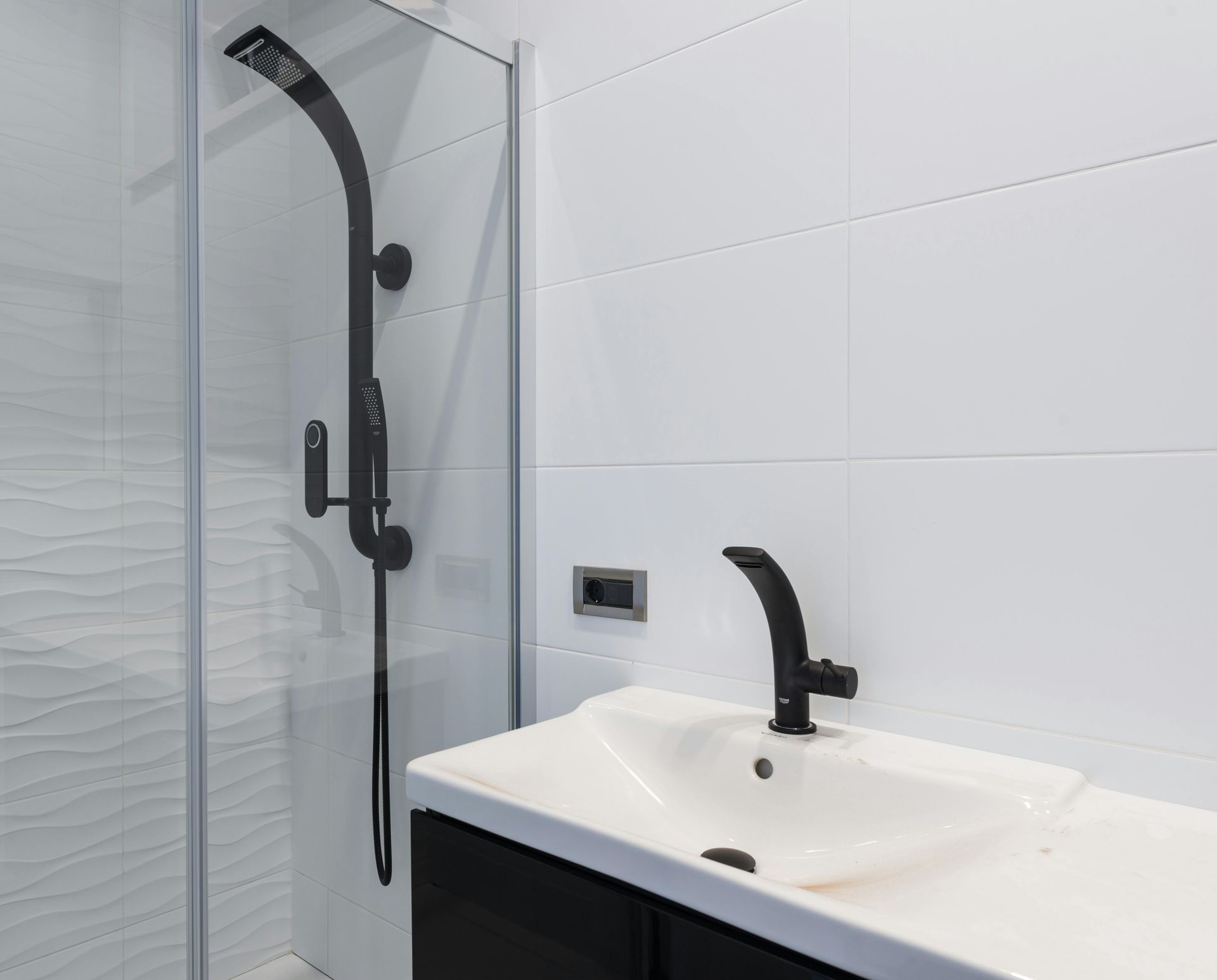 A bathroom with a sink , shower , and black faucet.