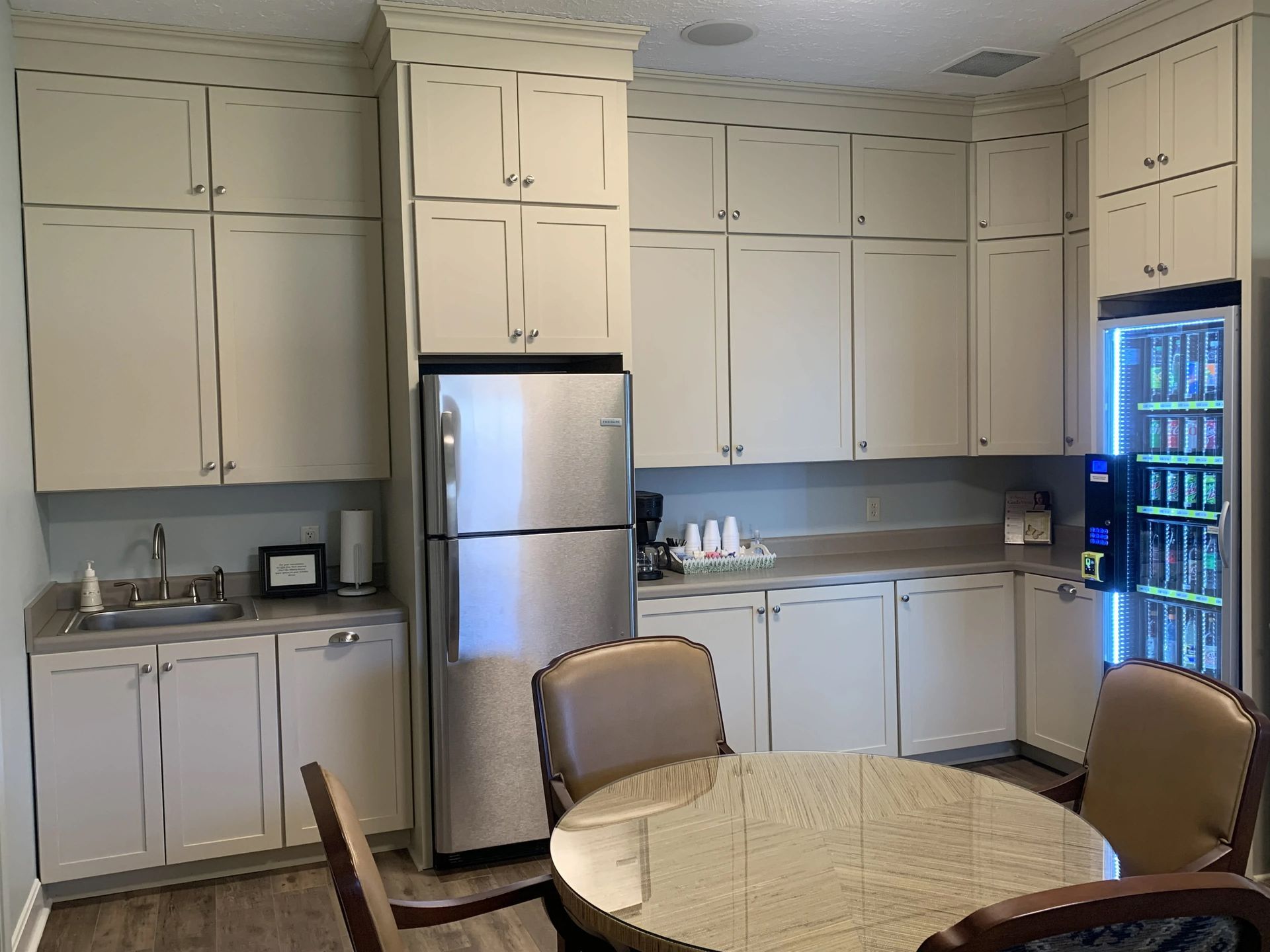 a kitchen with white cabinets , a refrigerator , a table and chairs .
