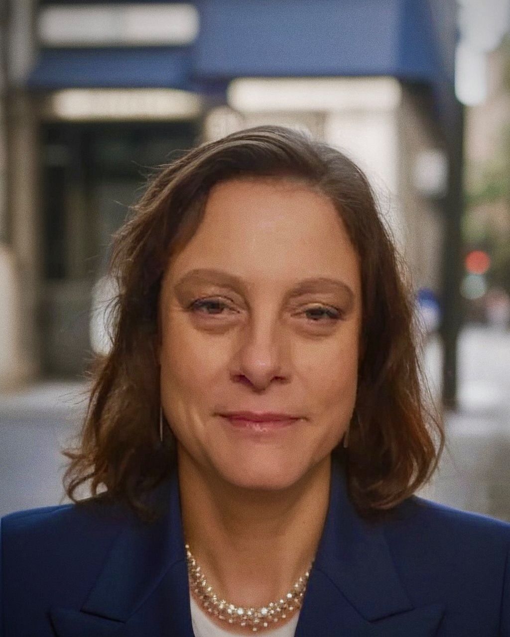 A woman in a green shirt is smiling for the camera.