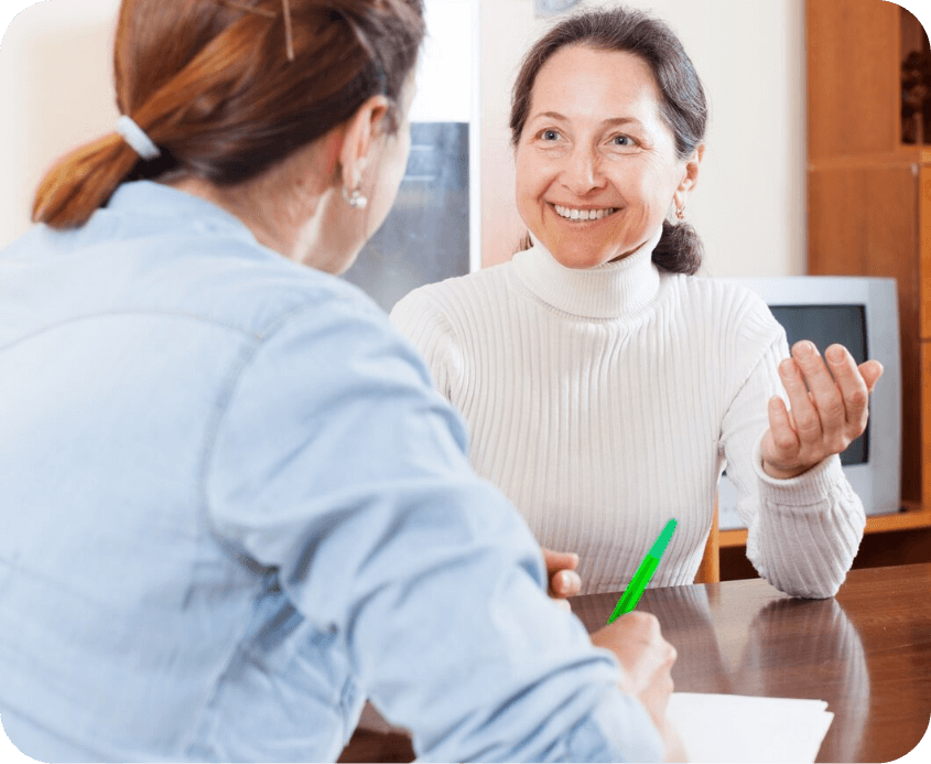 Two women are sitting at a table talking to each other.