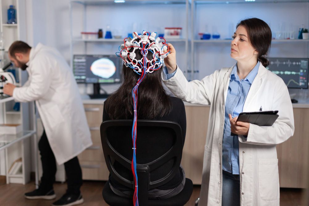 A woman is sitting in a chair while a doctor examines her head.