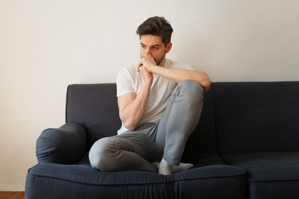 A man is sitting on a couch with his legs crossed.