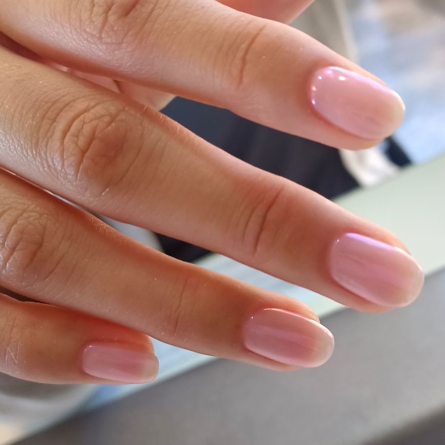 Un primer plano de las uñas rosas de una mujer.