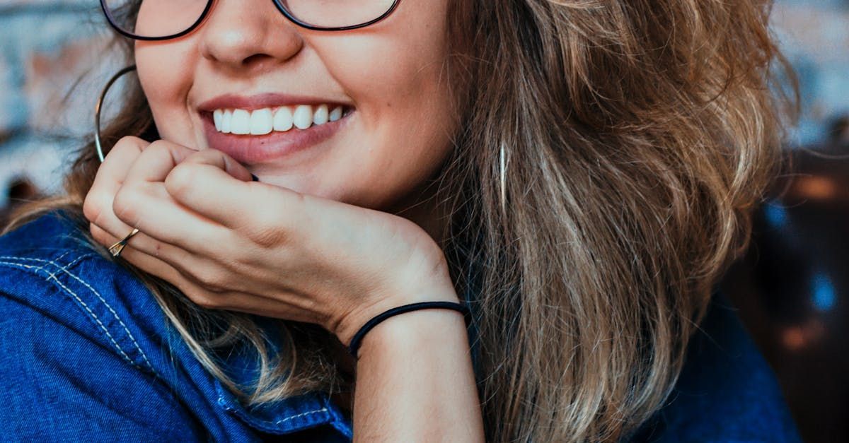 Una mujer que lleva gafas sonríe con la mano en la barbilla feliz de su elección de color