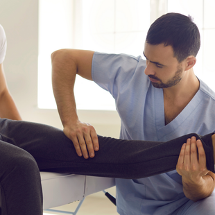 A man is stretching a woman 's leg on a table