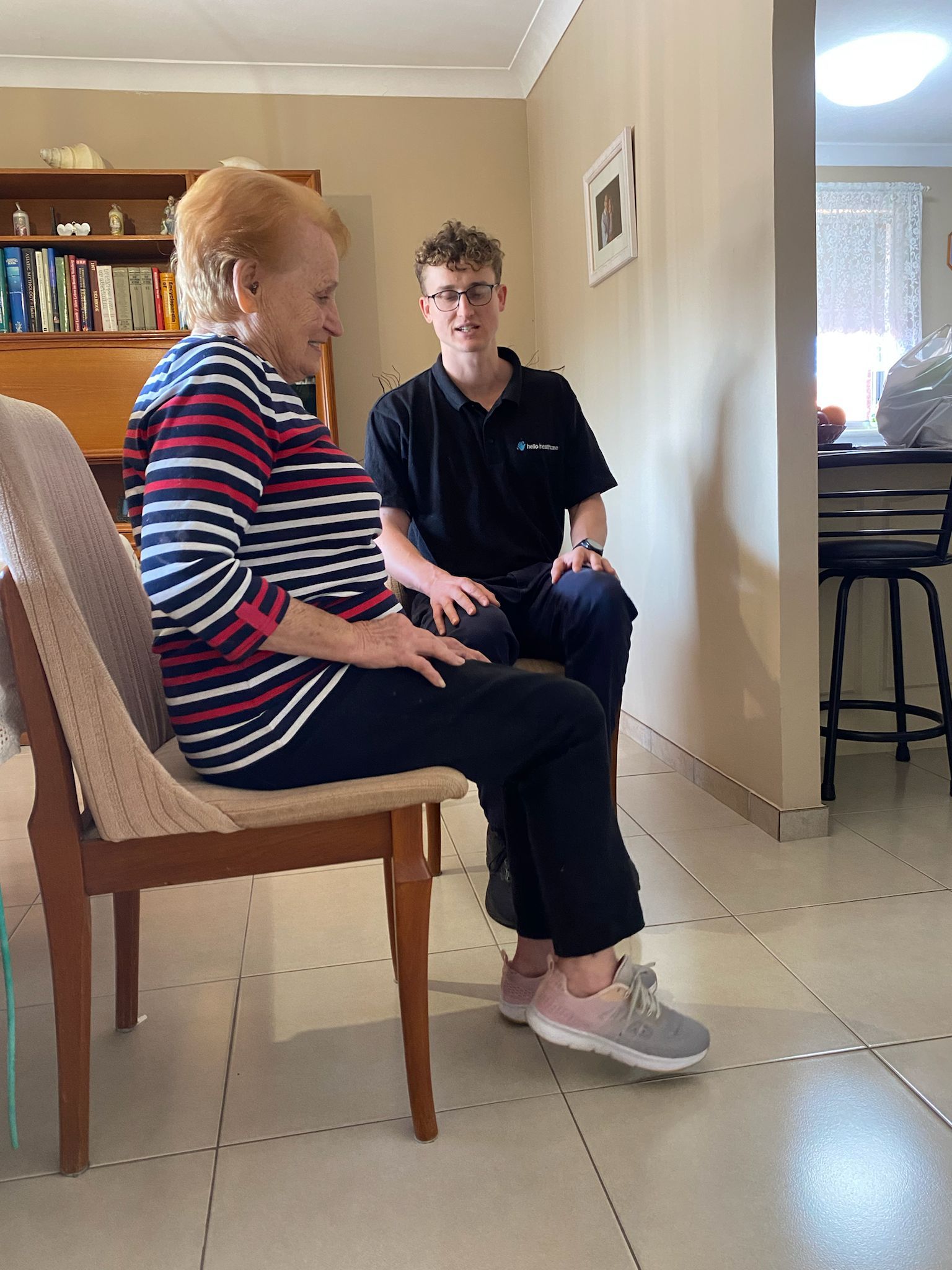 An older woman is sitting in a chair next to a younger man in a living room.