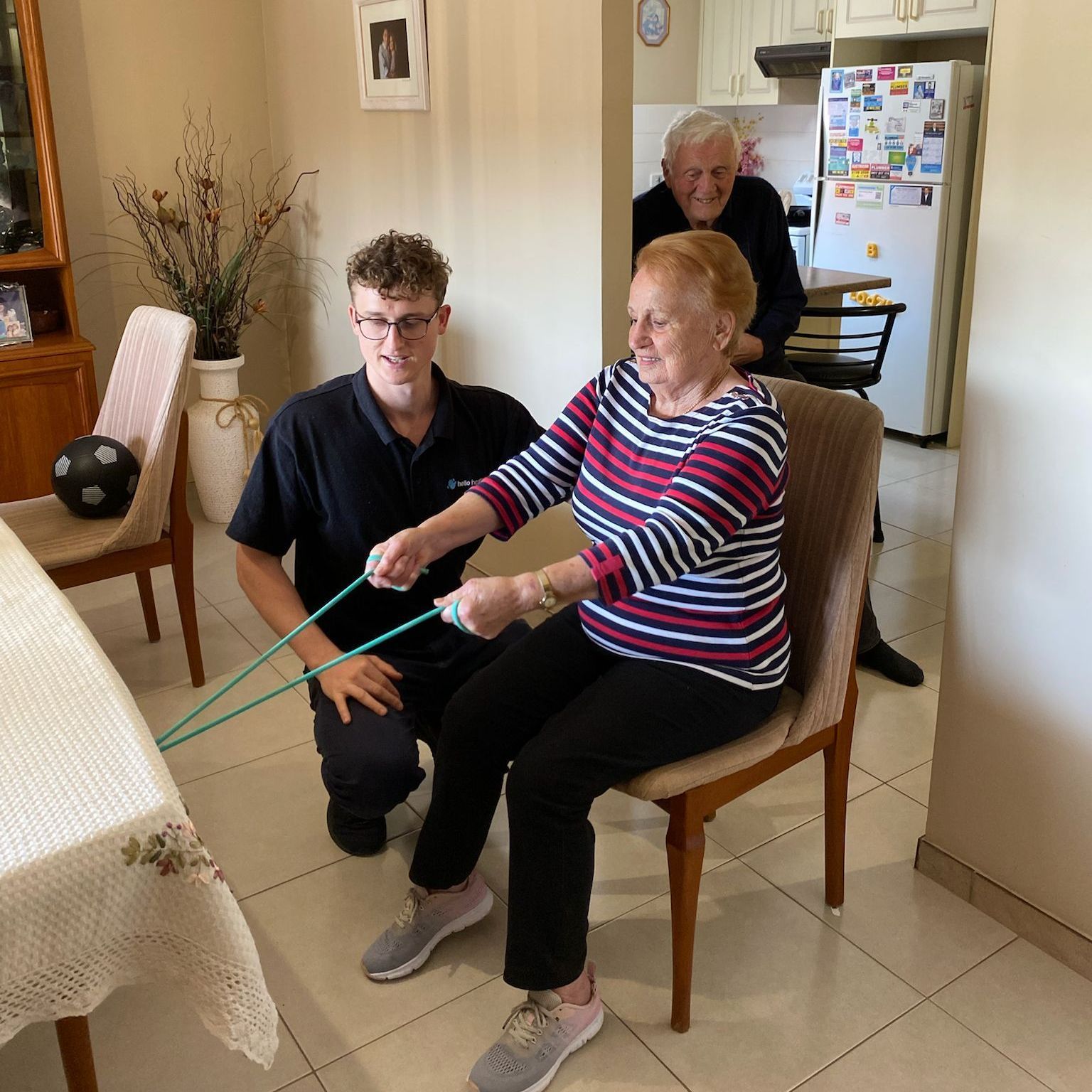 A man is helping an elderly woman with a resistance band