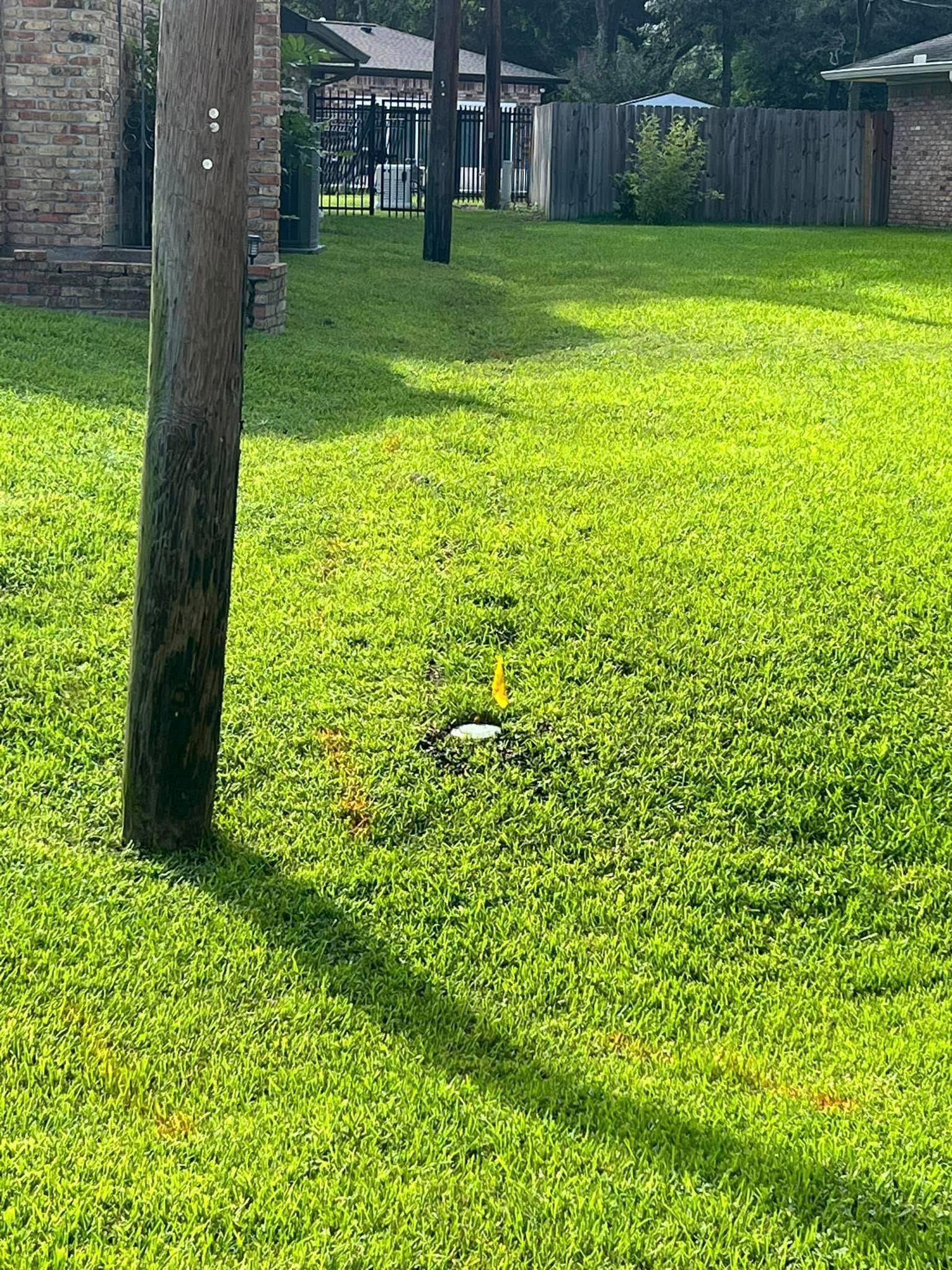 A lush green lawn with a wooden pole in the middle of it.