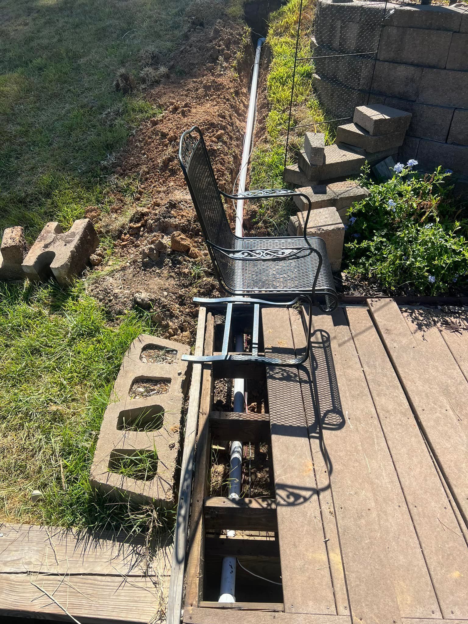A wooden deck with a chair and a pipe going through it.