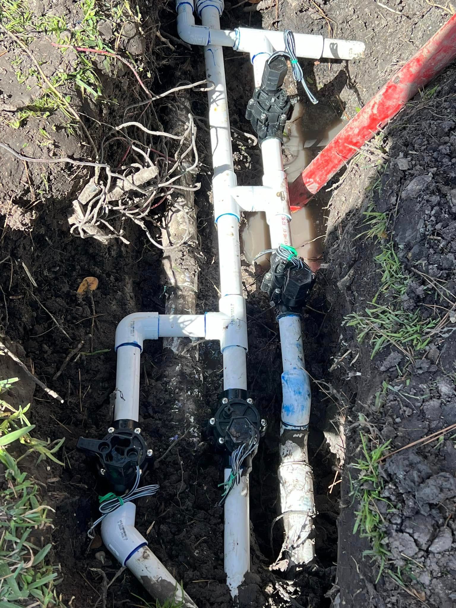A bunch of pipes are laying in the dirt.