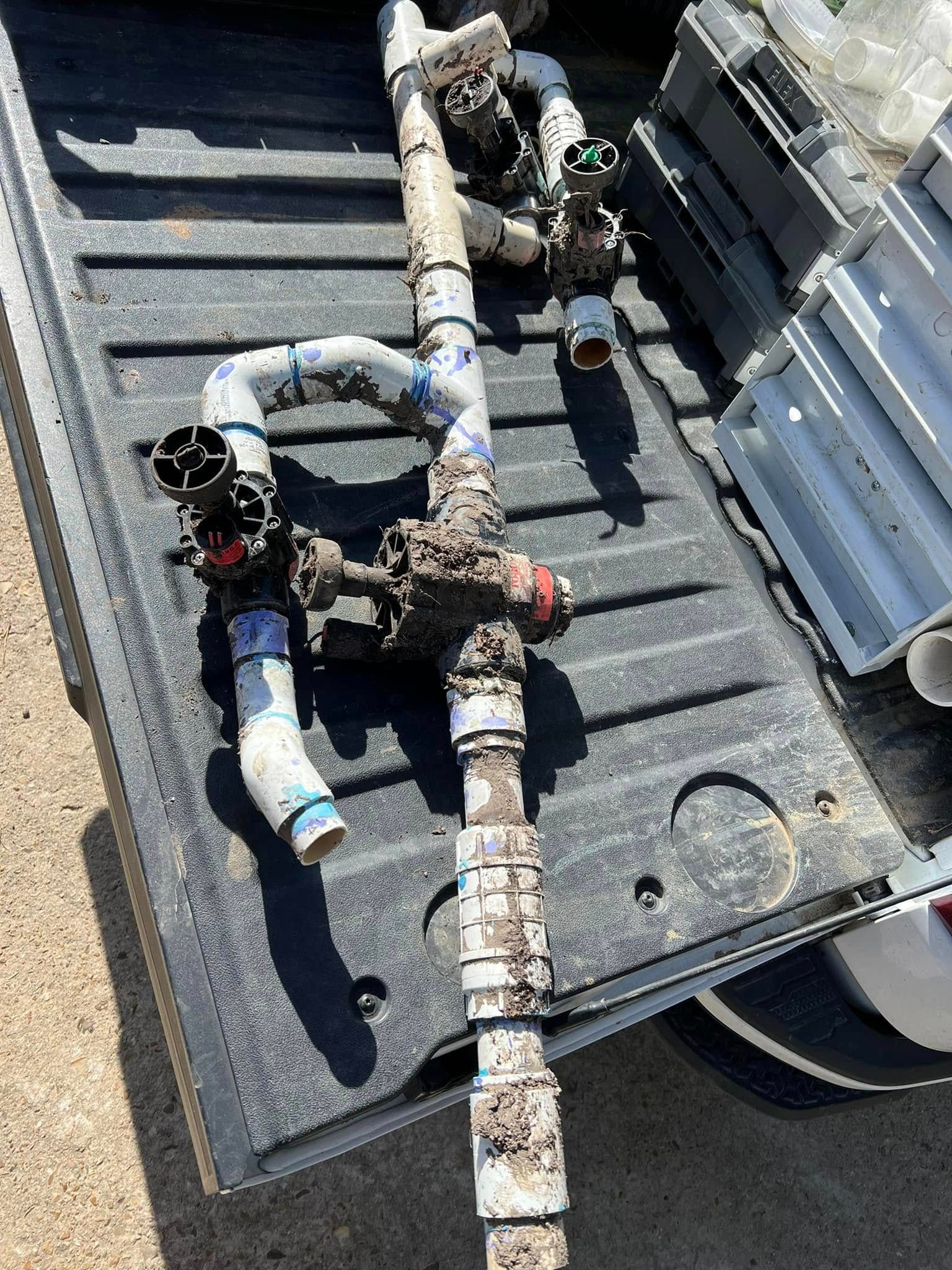 A bunch of pipes are laying on the back of a truck.