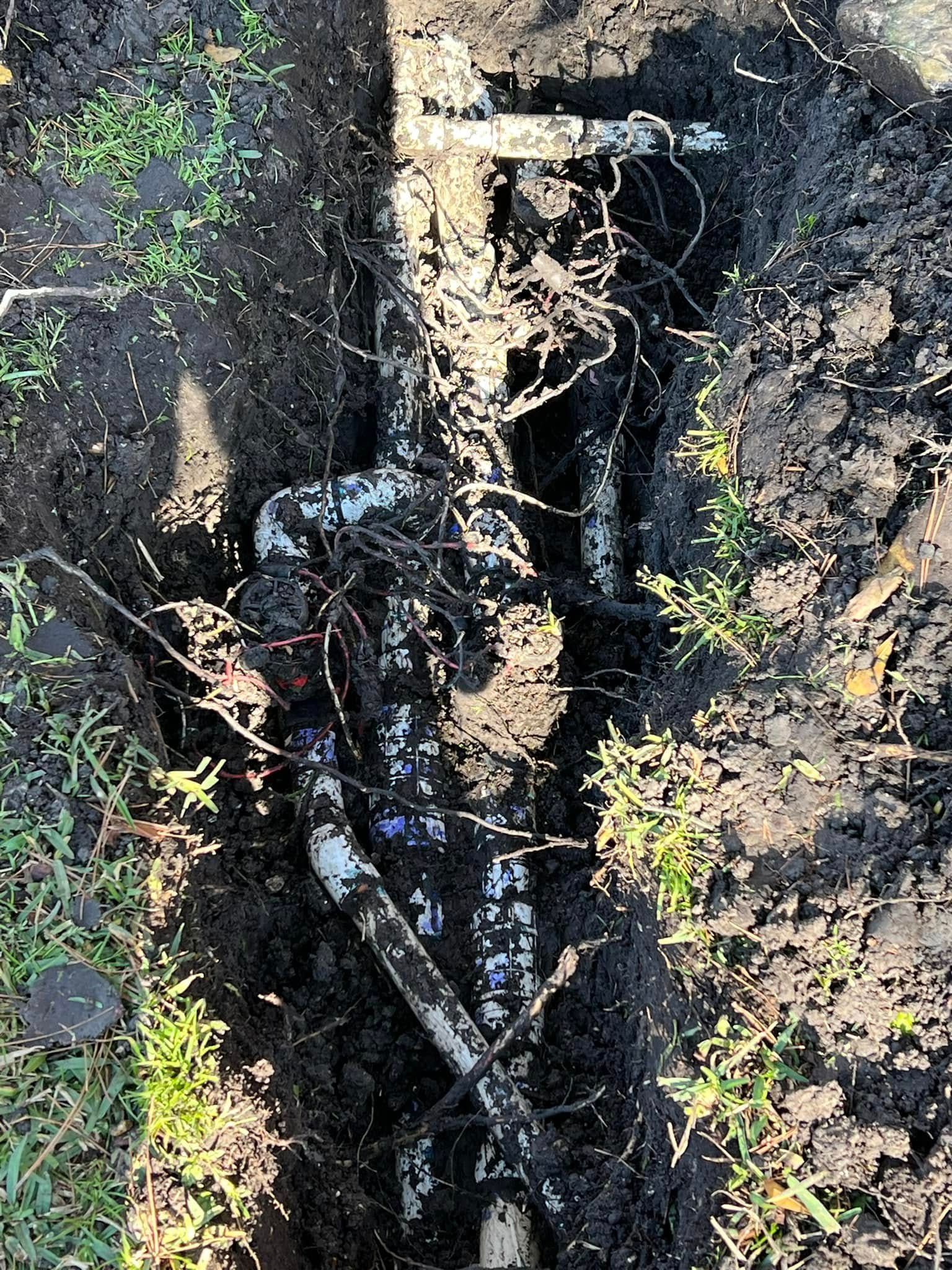 A pipe is laying in the dirt in a hole.