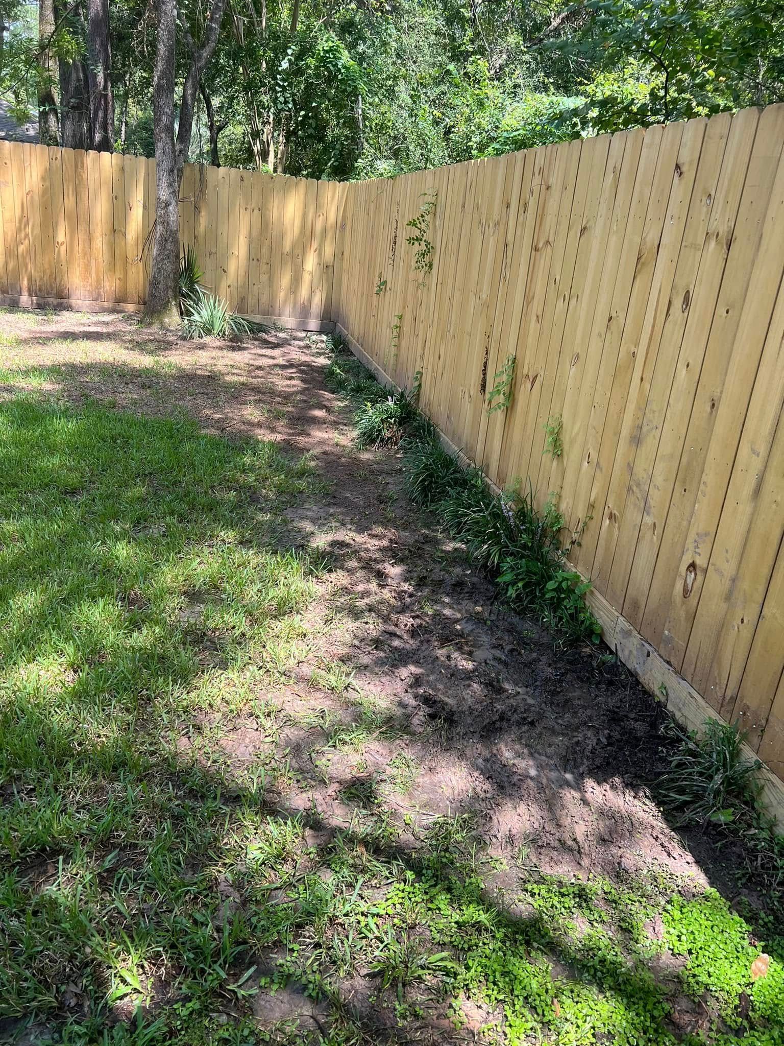 A wooden fence surrounds a lush green yard.