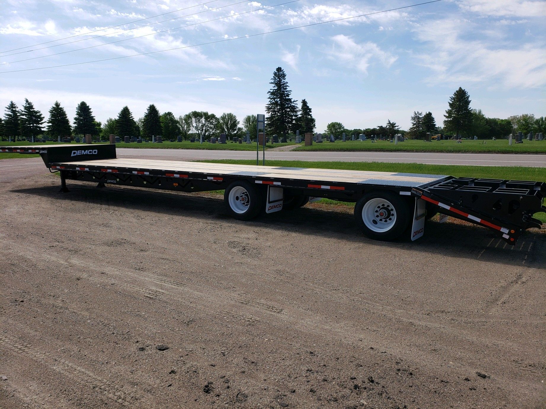 A flatbed trailer is parked on the side of a dirt road.