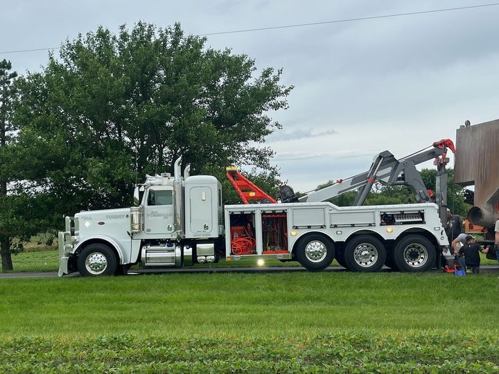 A white tow truck is parked on the side of the road.