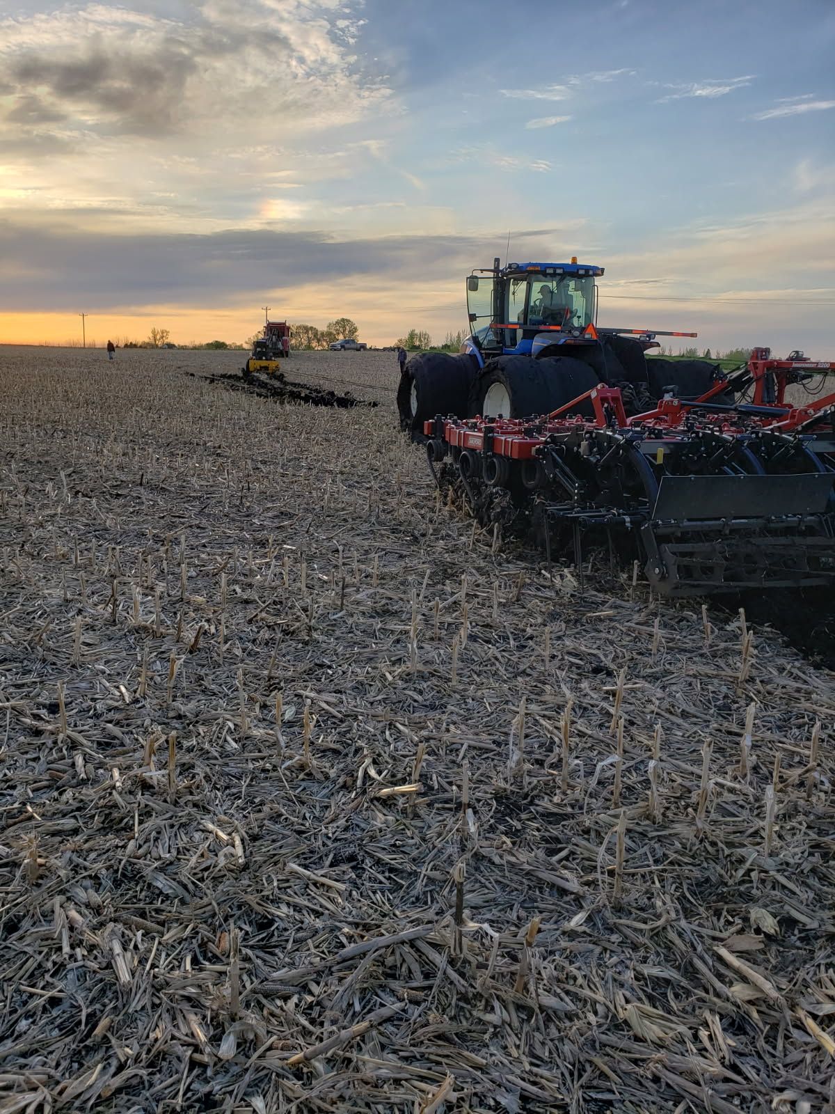 A tractor is plowing a field at sunset.