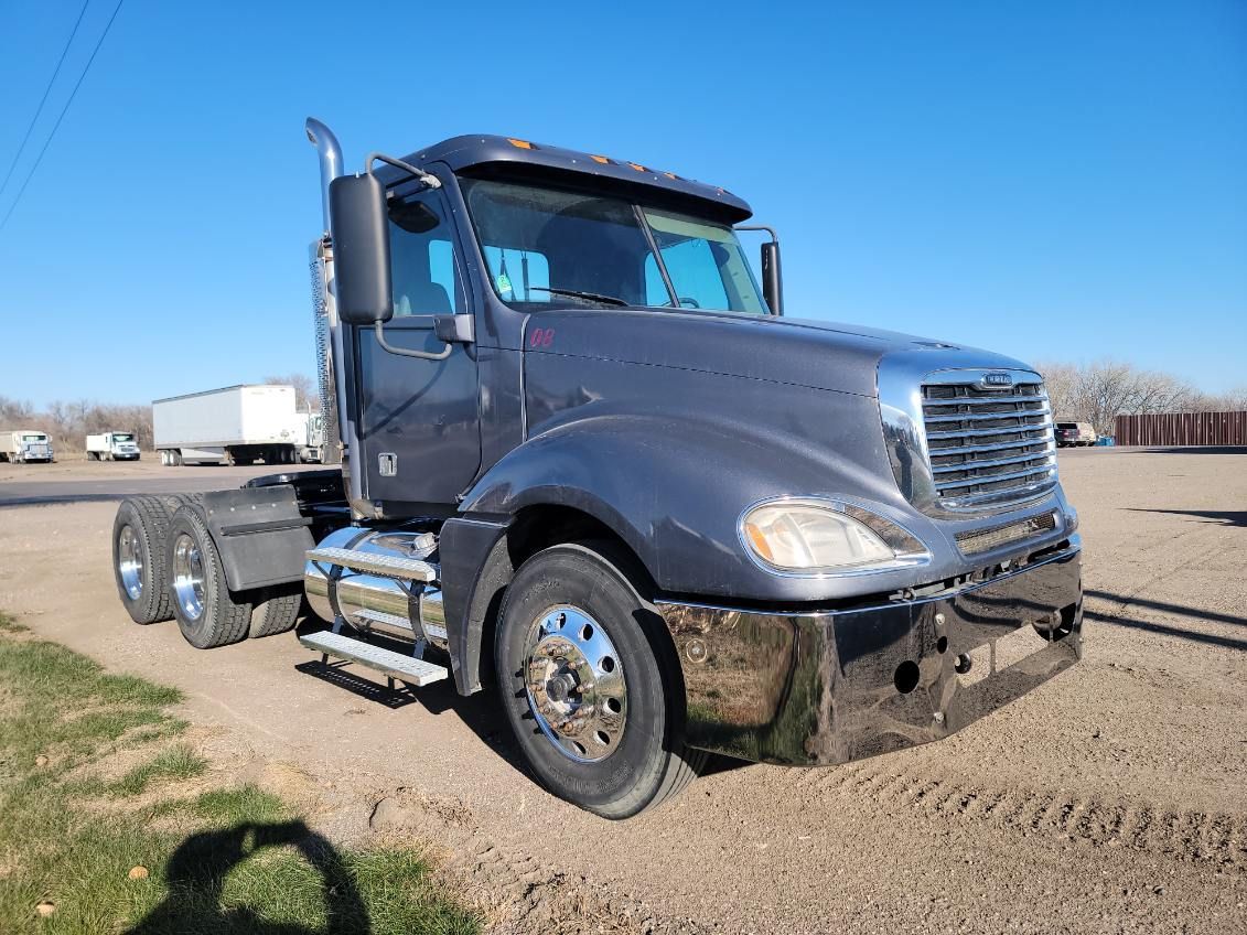 A large semi truck is parked in a dirt lot.