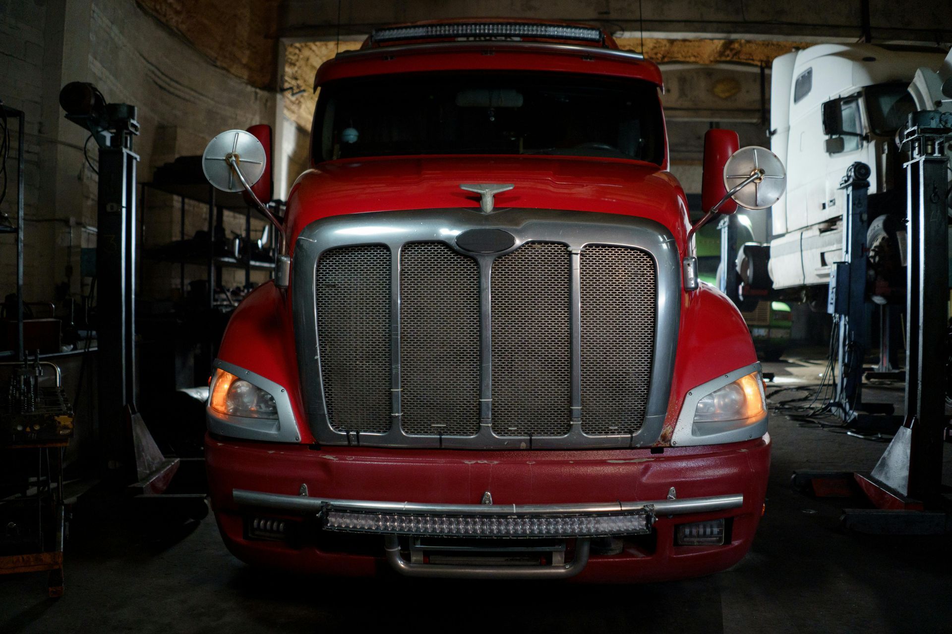 A red semi truck is parked in a garage.