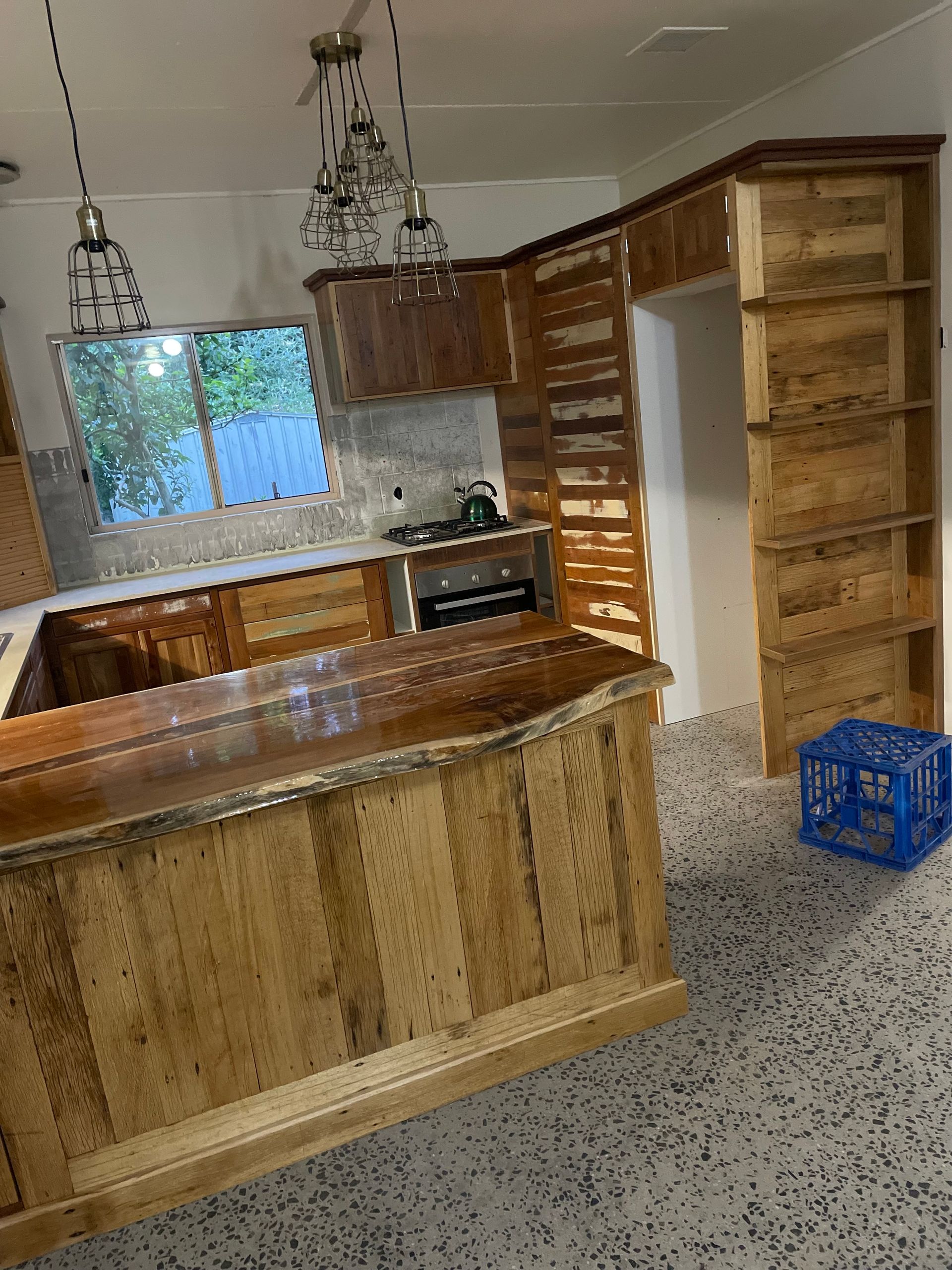 An Empty Kitchen With Wooden Floors and White Cabinets — Tim Thomas Carpentry in Magnetic Island, QLD