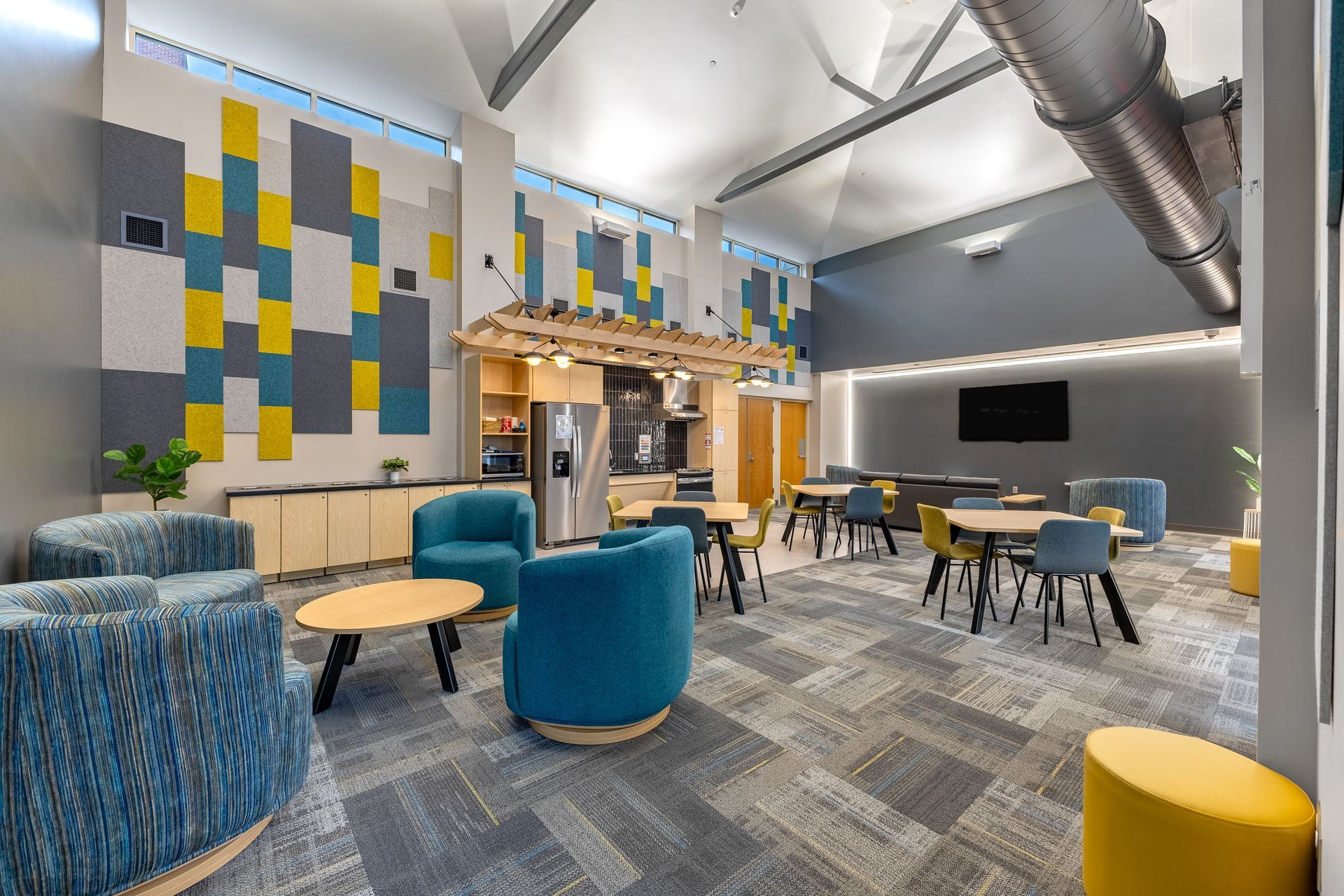 Penn State University's Eastview Terrace Kitchen with colorful patterned wall panels, various blue chairs, wooden tables, and an open kitchenette.