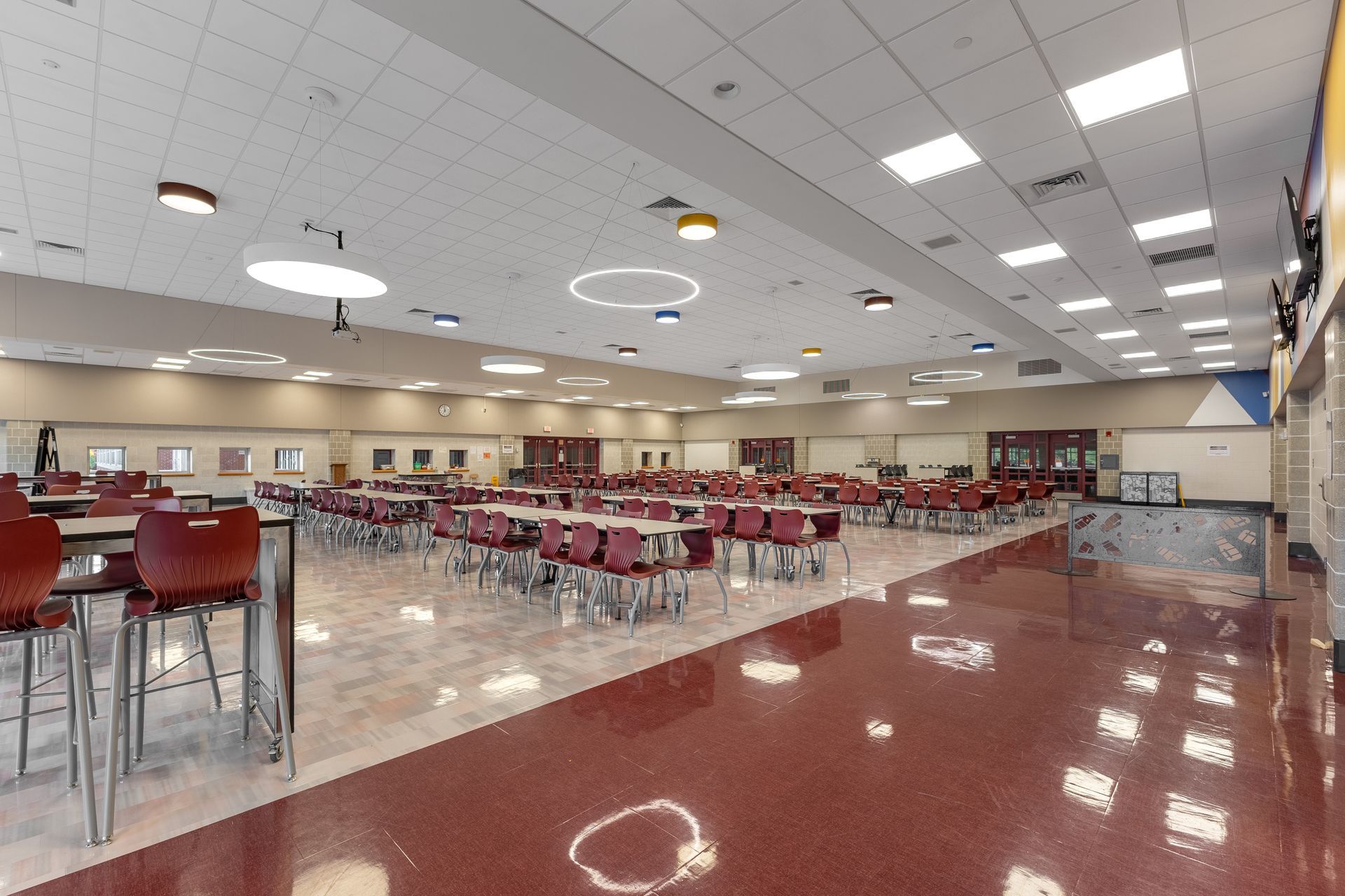 Mount Nittany Middle School Cafeteria with red chairs, white tables, and glossy floors under bright ceiling lights
