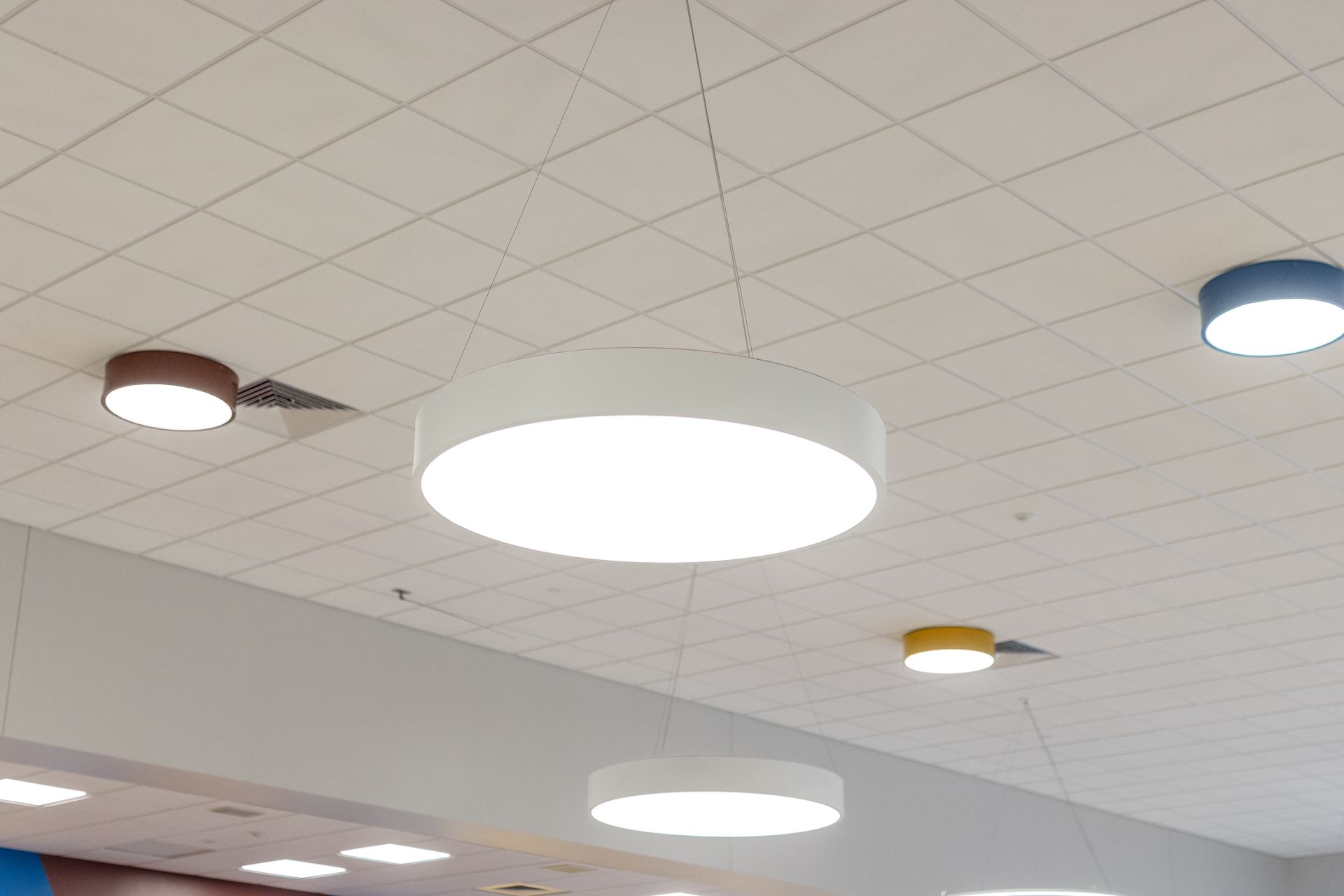 Mount Nittany Middle School Cafeteria's ceiling with recessed lights and a large round white light fixture above a room.