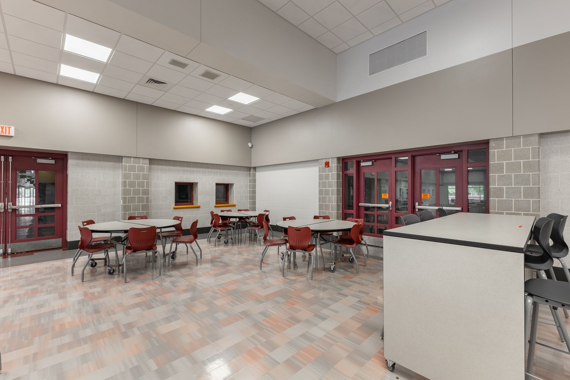 Mount Nittany Middle School Cafeteria with red chairs, round tables, tiled floor, and a serving counter.