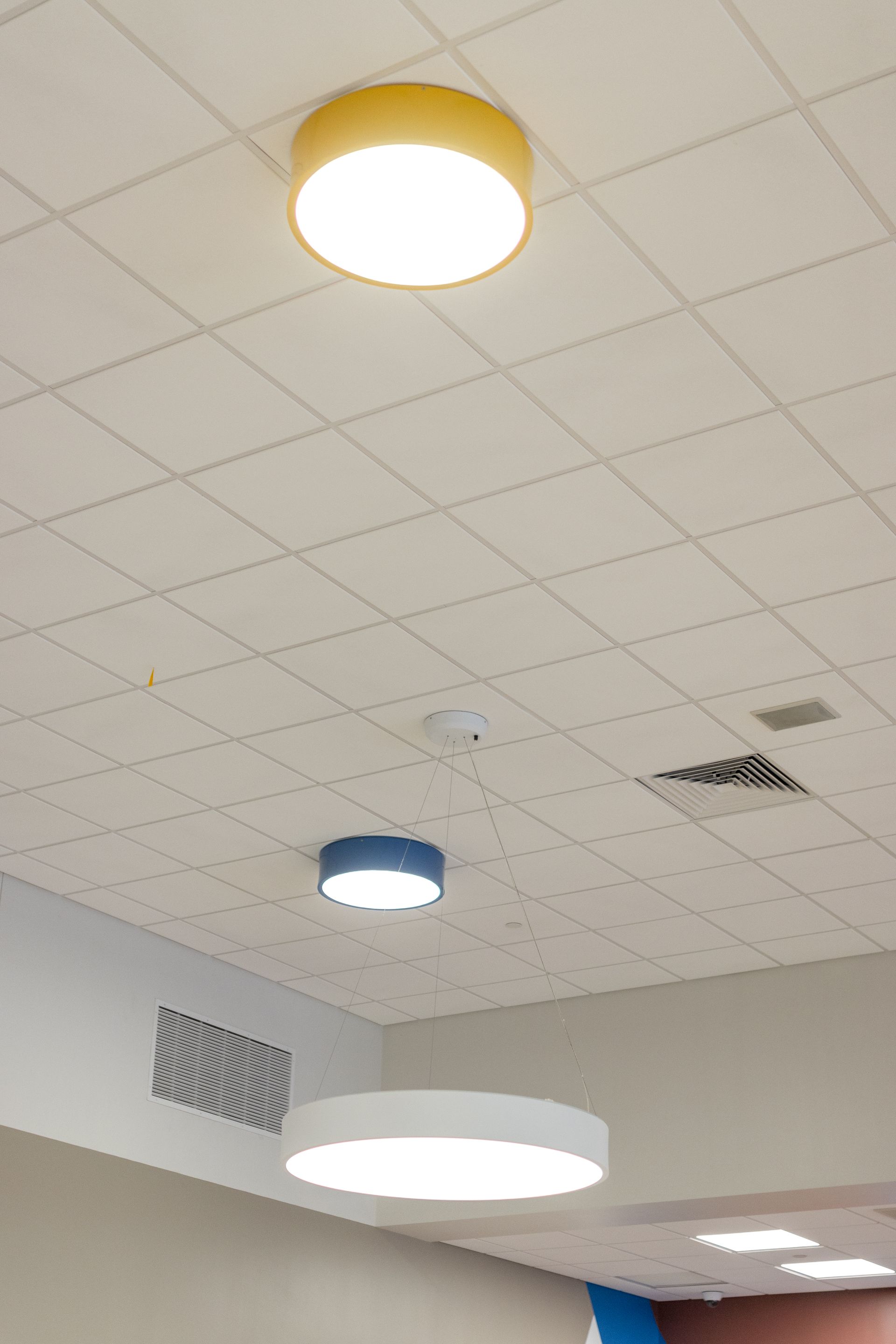 Mount Nittany Middle School Cafeteria's ceiling with several round light fixtures in a room with acoustic tiles.
