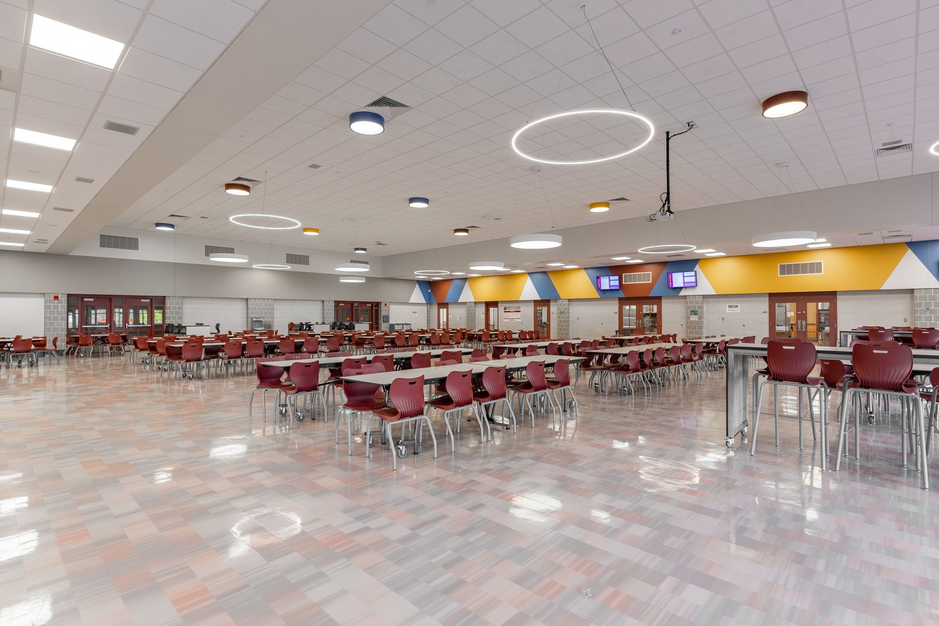 Mount Nittany Middle School Cafeteria with red chairs, long tables, and a bright ceiling in a large open room.