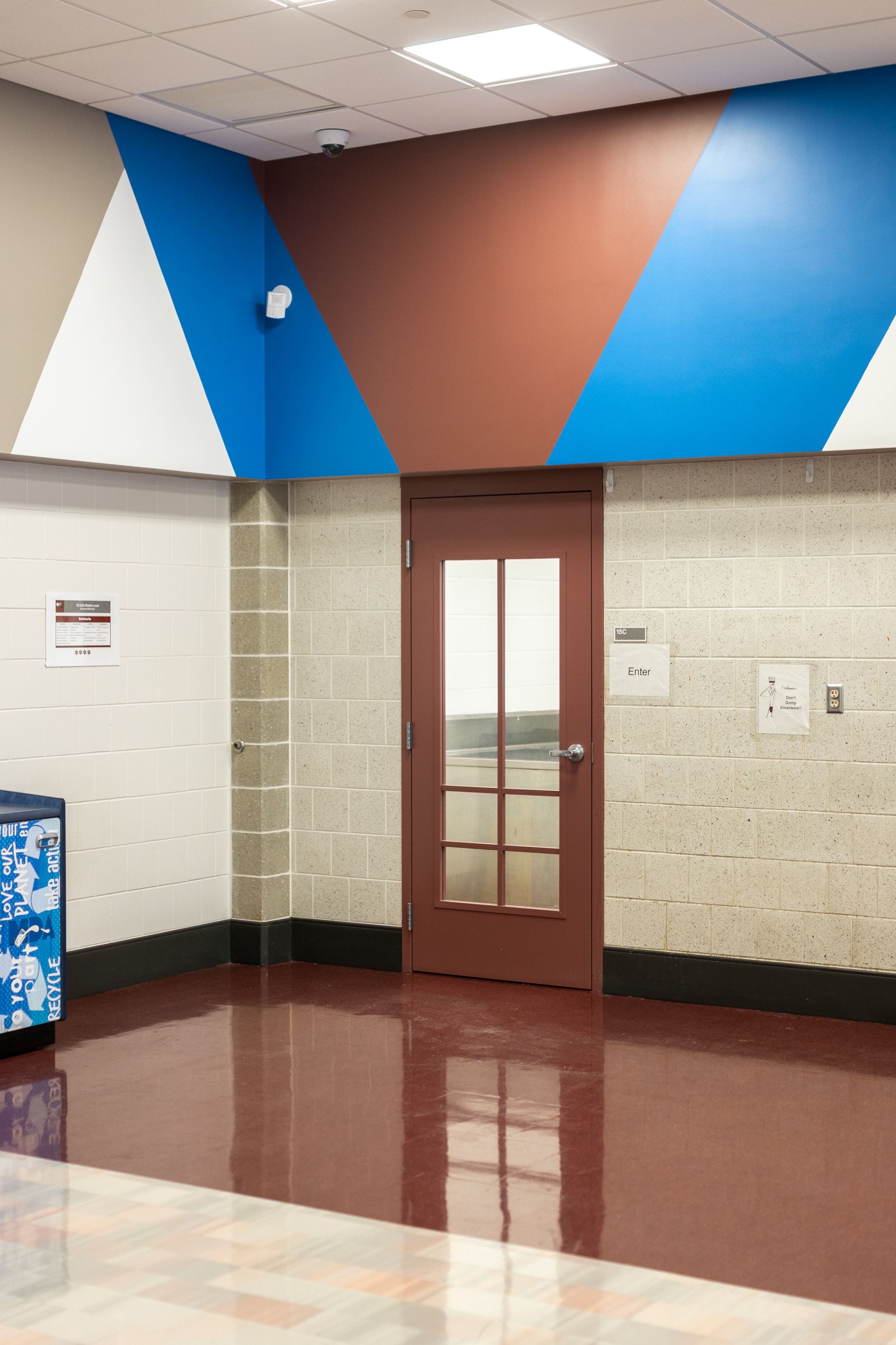 Mount Nittany Middle School Cafeteria's empty hallway with geometric blue, brown, and white wall panels and a closed door.