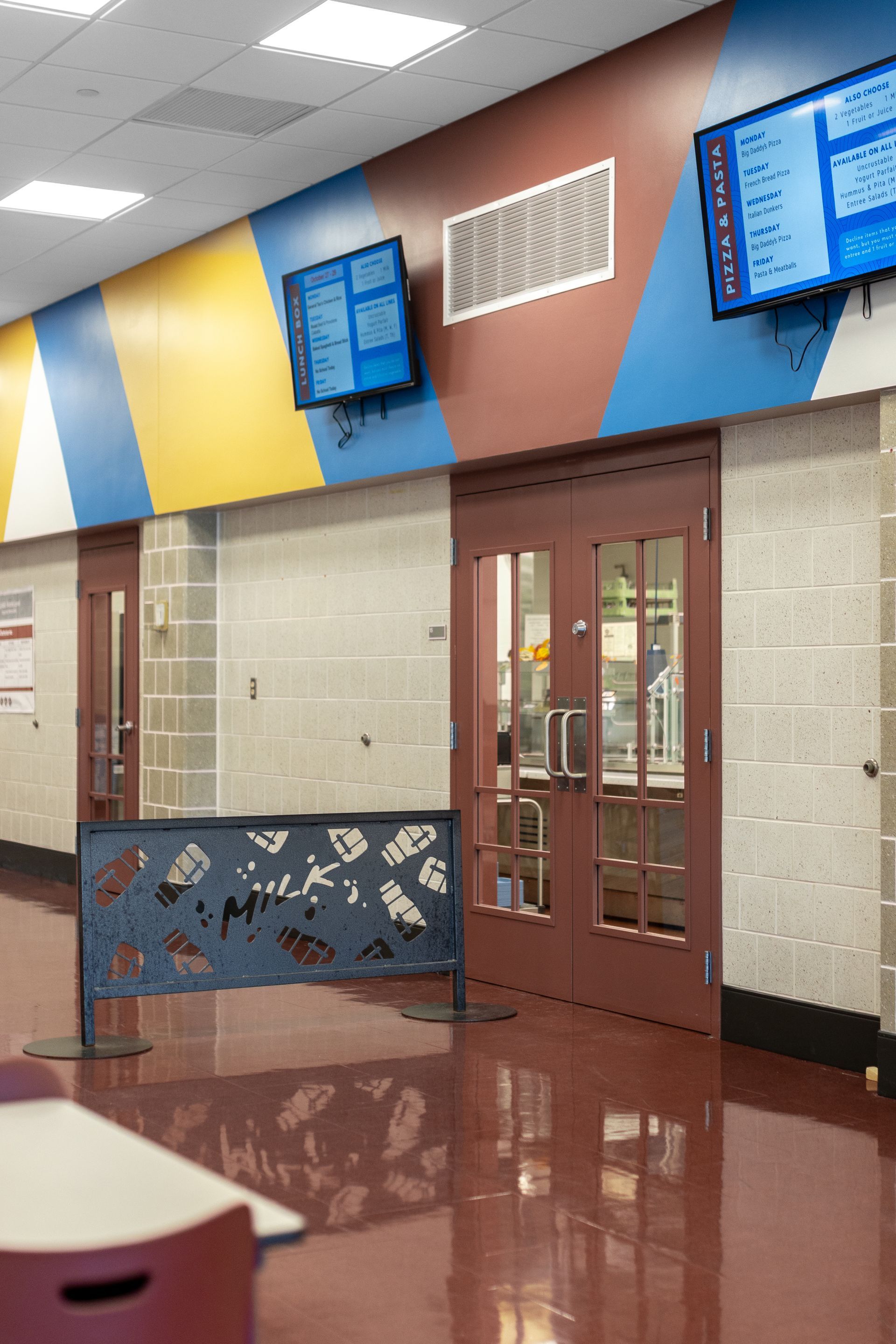 Mount Nittany Middle School Cafeteria's colorful hallway with double doors, blue wall panels, and a glossy floor in a school-like building