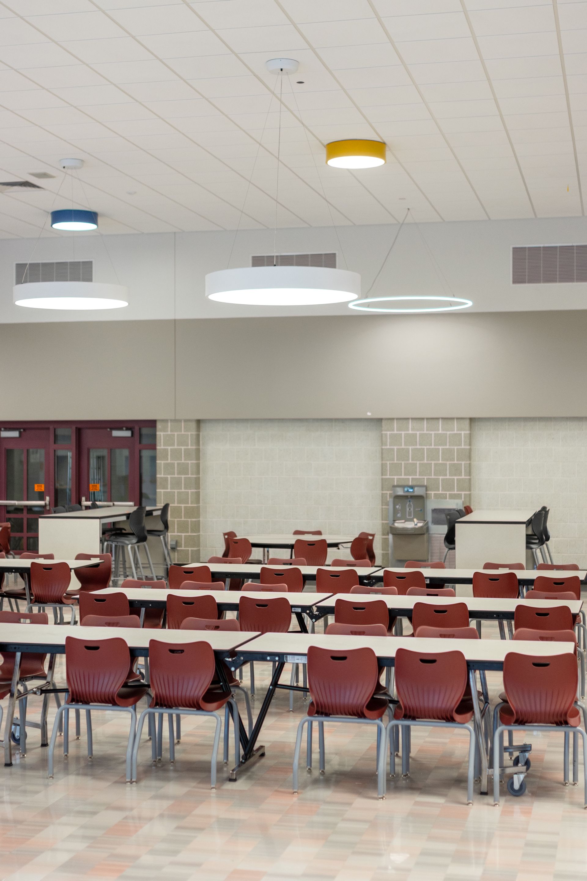Mount Nittany Middle School Cafeteria with rows of red chairs and tables under bright ceiling lights