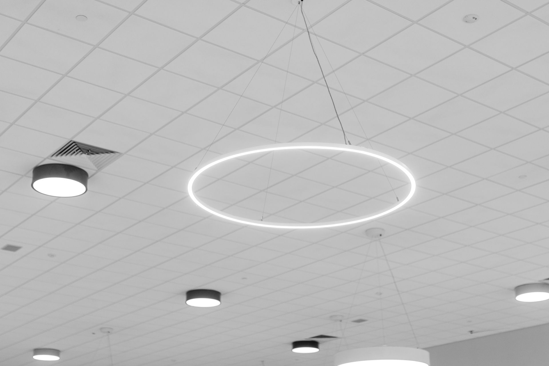 Mount Nittany Middle School Cafeteria's ceiling with recessed lights and a glowing circular ring light on a white tiled surface