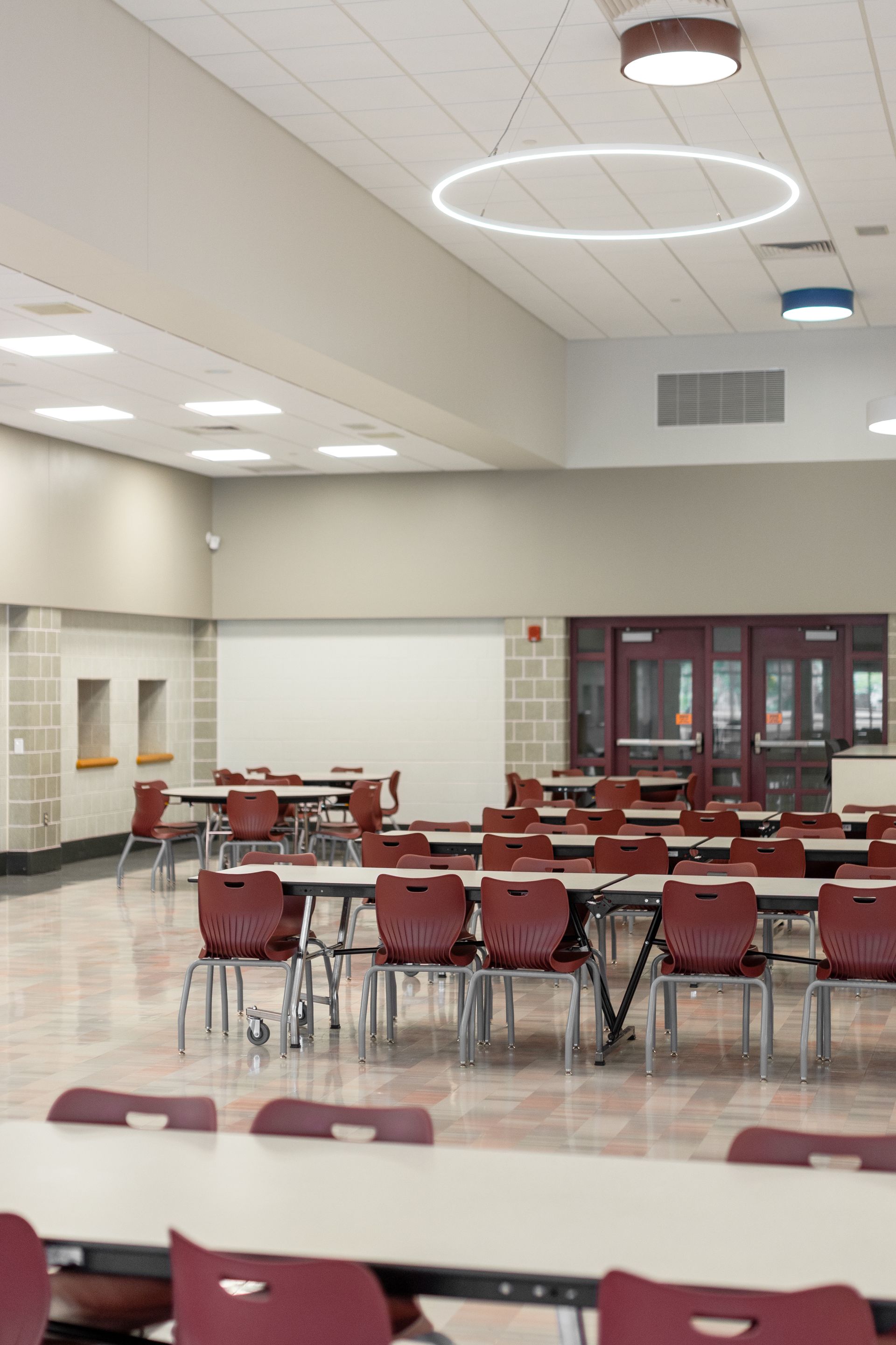 Mount Nittany Middle School Cafeteria with rows of red chairs and tables under bright ceiling lights.