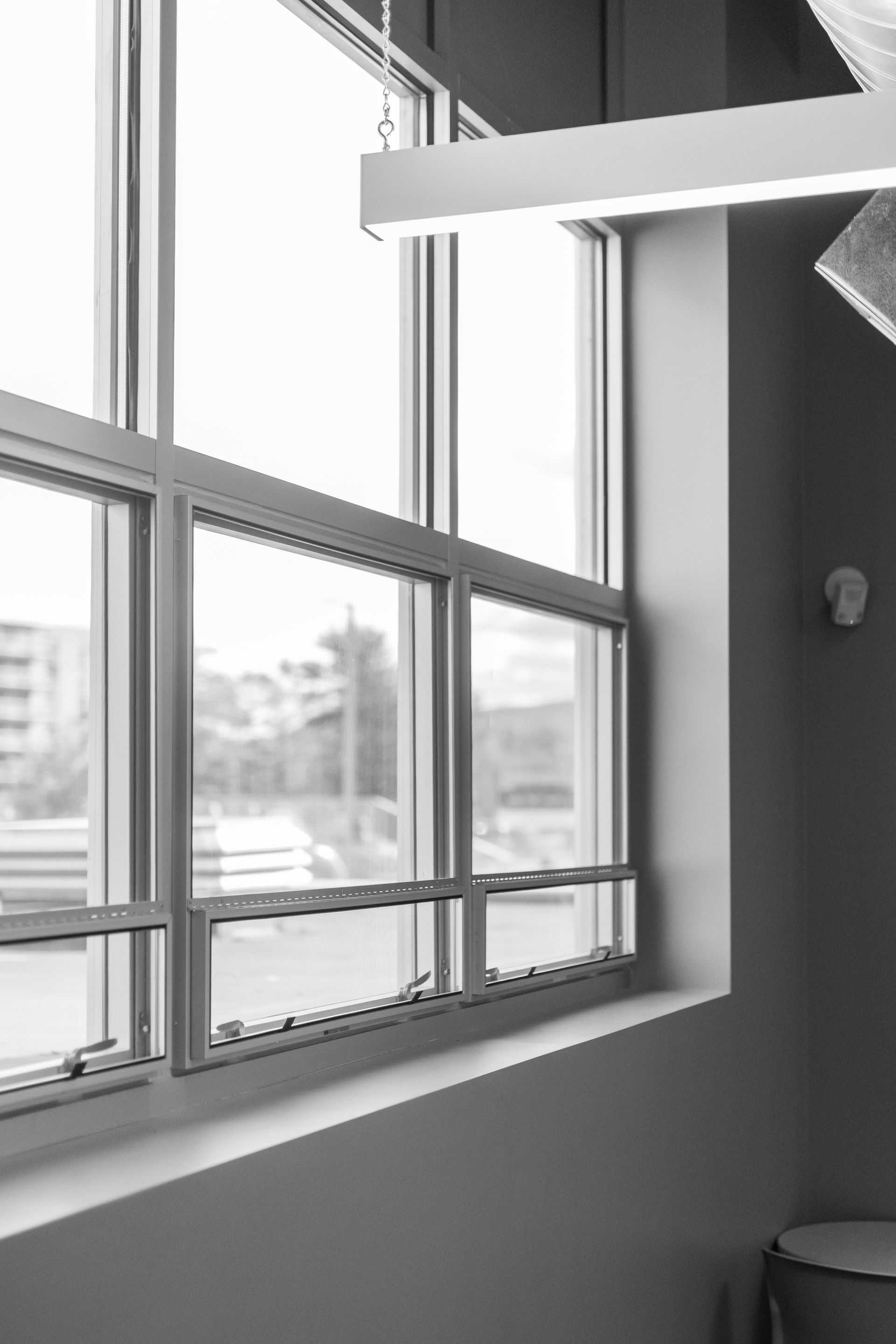 State College Area School District North Building's sunlit office window with blinds, white wall, and a dark corner shelf