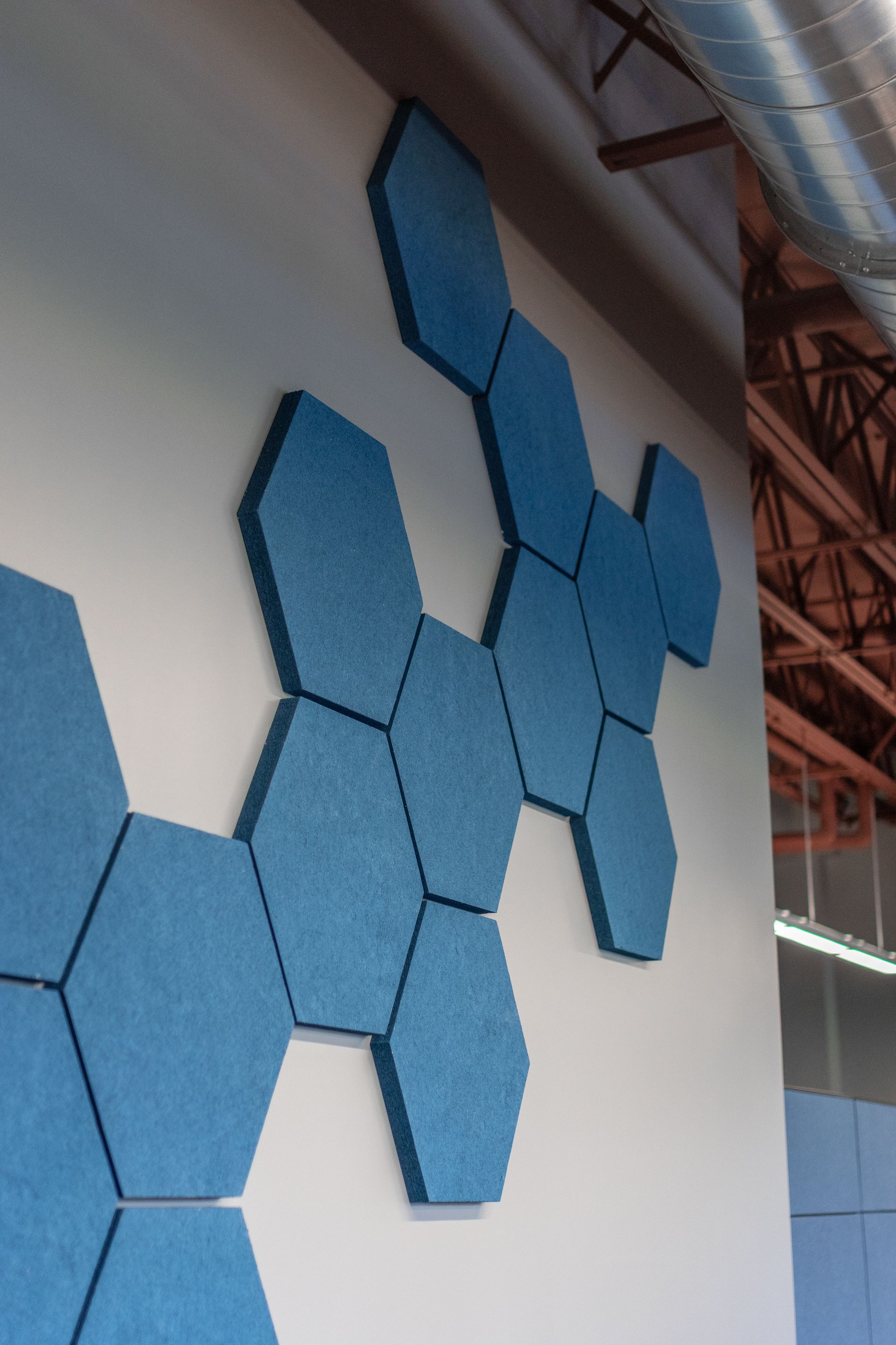 State College Area School District North Building's blue hexagonal wall tiles on an indoor wall near a ceiling and exposed beams