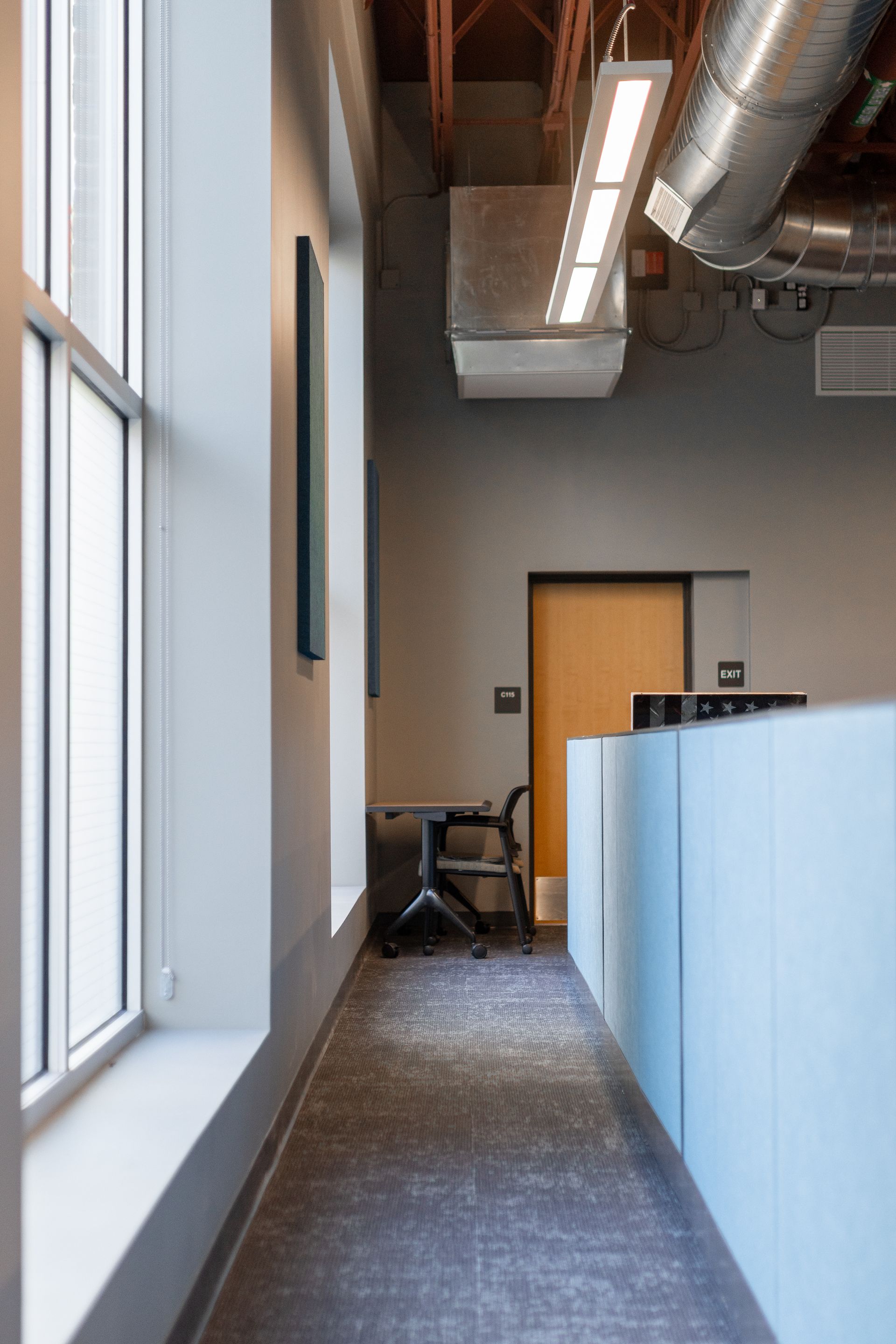 State College Area School District North Building's modern office hallway with windows, exposed ducts, and a closed wooden door at the end.
